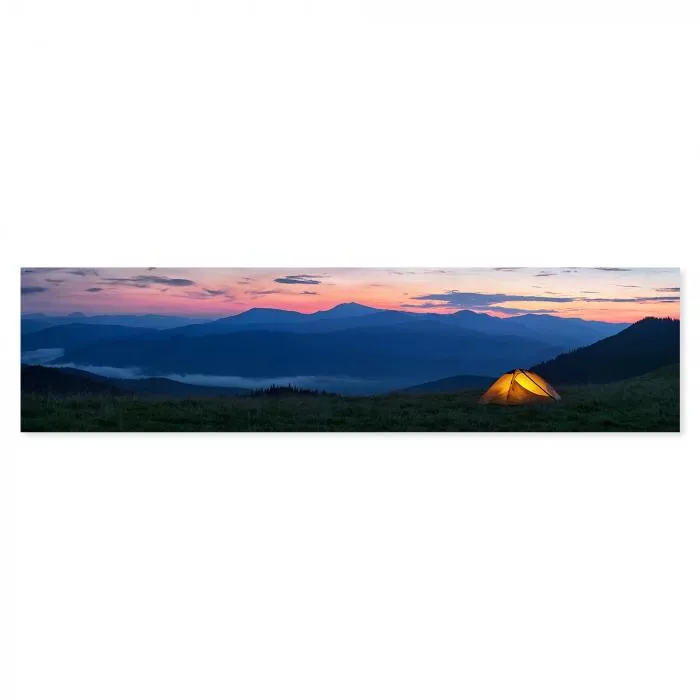 Beleuchtetes Zelt auf Wiese, Blick auf Bergsilhouette im Abendlicht.