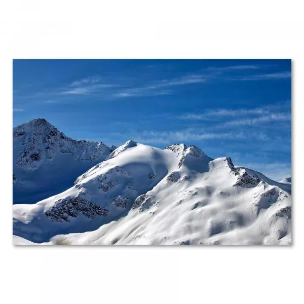 Gipfel schneebedeckter Berge ragen in den blauen Himmel mit leichten Wolken.