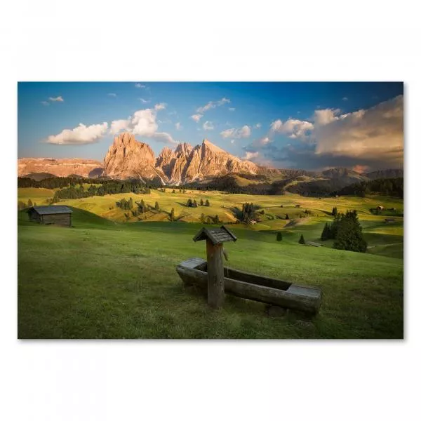 Alpenglühen: Eine Holzhütte auf einer Wiese, die Gipfel der Dolomiten erstrahlen im Sonnenuntergang.