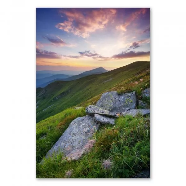 Sonnenuntergang, Berggipfel in warmem Licht, Steine auf grüner Wiese.