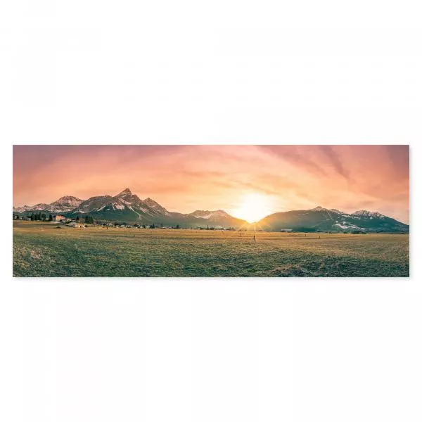 Sonnenaufgang über Bergpanorama, schneebedeckte Gipfel, grüne Wiesen.