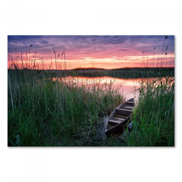 Holzboot am Seeufer, farbenfroher Sonnenuntergang, Spiegelung im Wasser.