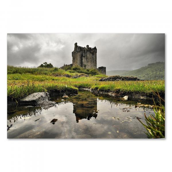 Eilean Donan Castle spiegelt sich in einem kleinen See, umgeben von Wiesen, wartet auf Besucher.