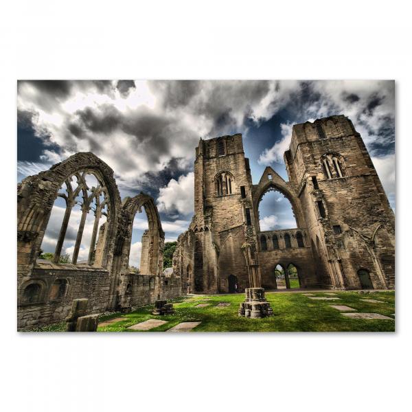 Ruine einer gotischen Kirche mit hohen Bögen, der Himmel bewölkt, kontrastiert mit grünem Rasen.