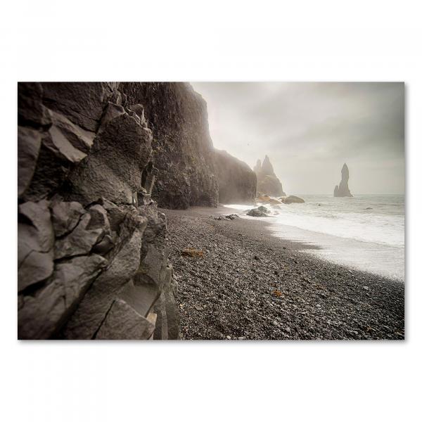 Schwarz-Weiß-Foto: Schwarzer Strand (Island), schroffe Felsen, düstere Stimmung.