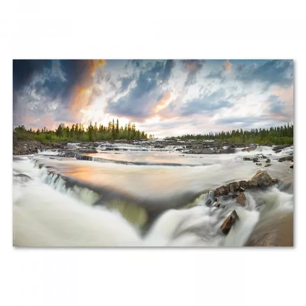 Ein Fluss in Lappland ergießt sich in Kaskaden, während der Himmel in warmen Farben eines Sonnenuntergangs erstrahlt.