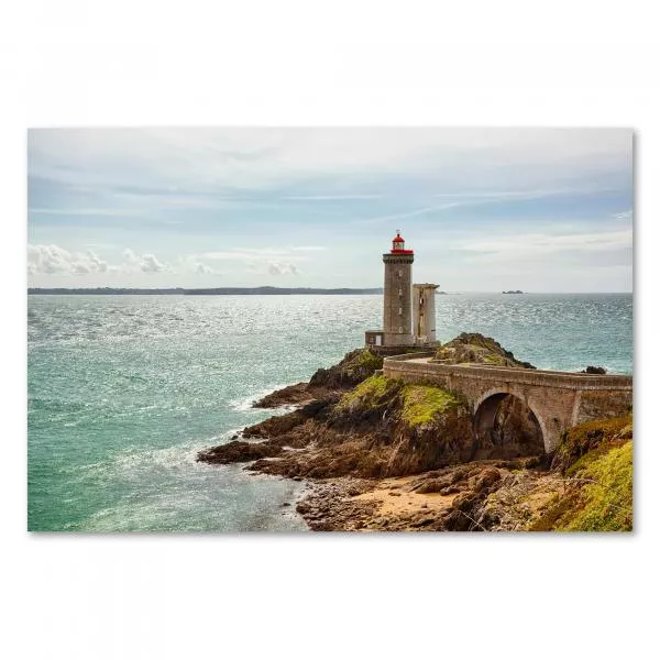 Leuchtturm auf felsiger Insel, Steinbrücke, blaues Meer & bewölkter Himmel.