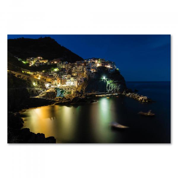 Malerische Häuser von Manarola in der Nacht spiegeln sich im Mittelmeer: ein Anblick wie aus dem Bilderbuch.