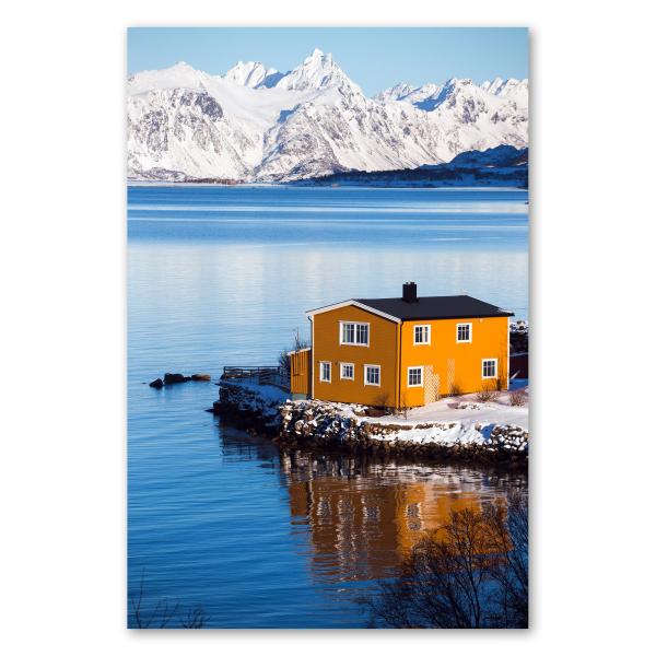 Gelbes Haus am Fjord, schneebedeckte Berge, Spiegelung im Wasser.