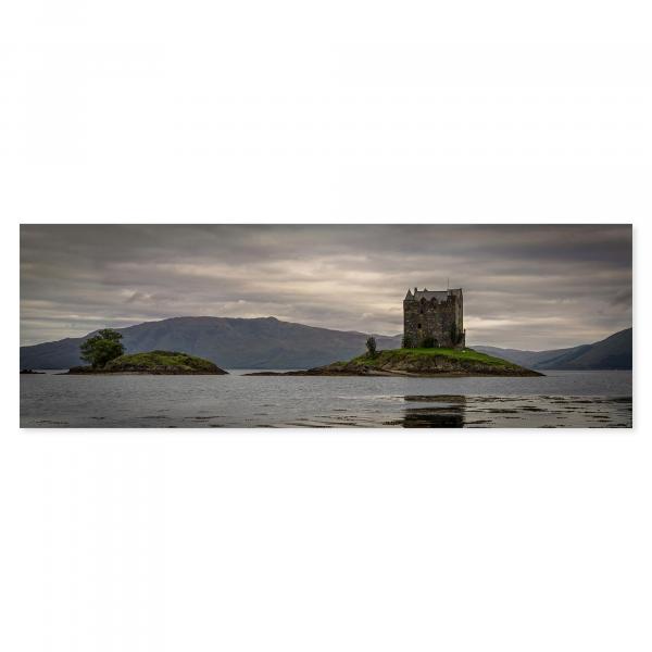 Malerische Insellandschaft in Schottland mit historischem Schloss, majestätische Berge erheben sich im Hintergrund.