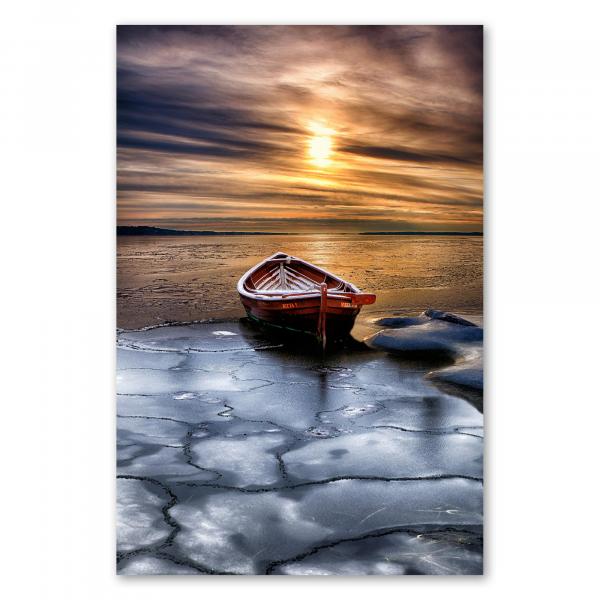 Kleines Holzboot auf gefrorenem See, Sonne untergeht und Himmel erstrahlt in warmen Farben.