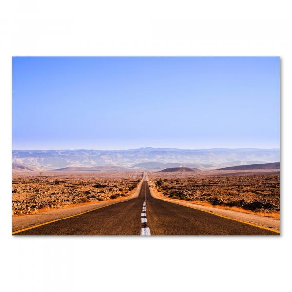 Eine schnurgerade Straße führt durch eine weite Wüstenlandschaft in Richtung Horizont.