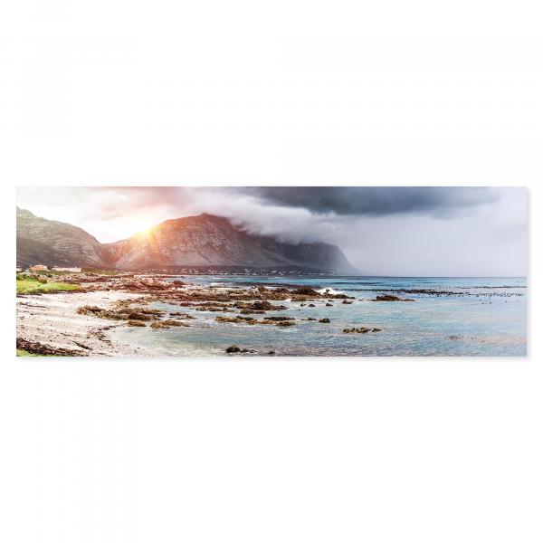 Dramatische Lichtstimmung an der Küste Südafrikas: Die Sonne taucht Felsen und Meer in warmes Licht.