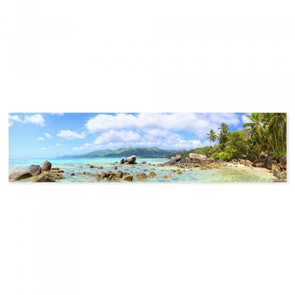 Tropischer Strand auf den Seychellen: Türkisblaues Wasser, Felsen, Palmen.