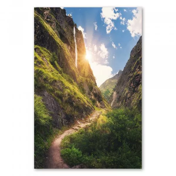 Wasserfall stürzt an Felswand in die Tiefe, Wanderweg durch grüne Landschaft.