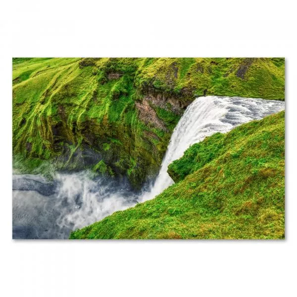 Wasserfall stürzt über moosbewachsene Felsen, Gischt steigt wie Nebel auf.