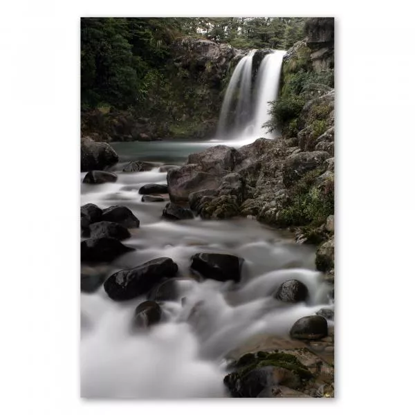 Idyllischer Wasserfall ergießt sich in smaragdgrünen See, umgeben von dichtem Wald, bietet Ruhe und Schönheit.