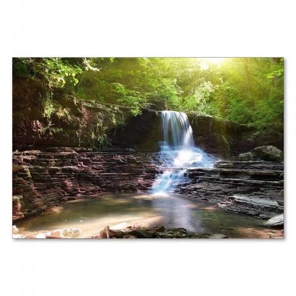 Ein idyllischer Wasserfall stürzt über Felsen in einen Teich – die Magie des Waldes in einem Bild.