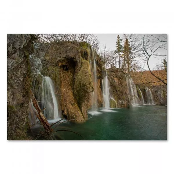 Idyllischer Wasserfall ergießt sich in einen smaragdgrünen See, umgeben von Wald, ruhiger Ort der Schönheit.