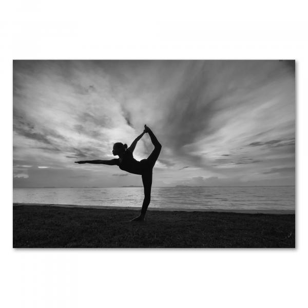 Eine Frau in einer eleganten Yogapose am Strand - ein harmonisches Schwarz-Weiß-Motiv voller Balance.