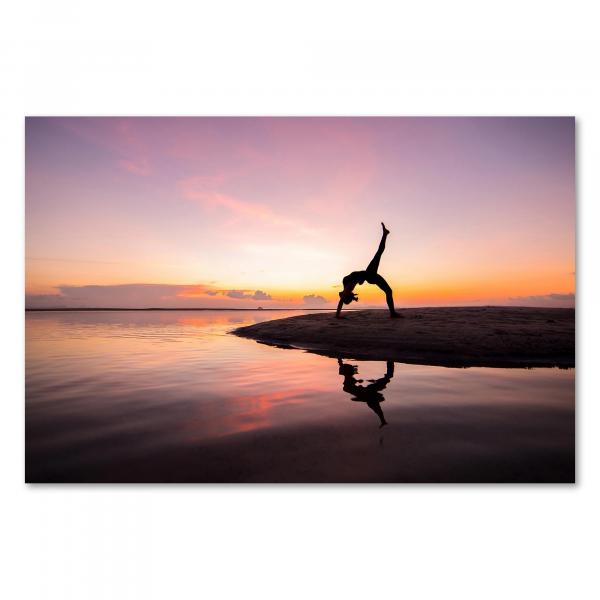 Eine Frau macht Yoga am Strand im Sonnenaufgang – ein Bild voller Harmonie und Energie.